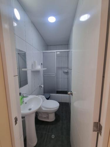 a white bathroom with a toilet and a sink at Habitación para Estudiantes in Lima