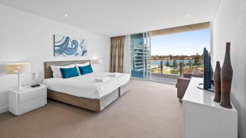 a white bedroom with a bed and a large window at Bayview 608 in Mandurah