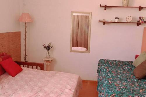 - une petite chambre avec un lit et un miroir dans l'établissement Casa de praia Pitória São Pedro da Aldeia, à São Pedro da Aldeia