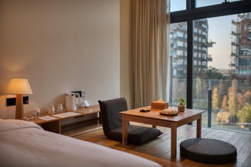ein Hotelzimmer mit einem Schreibtisch, einem Bett und einem Tisch in der Unterkunft Taihua Wutong Hotel in Bao'an