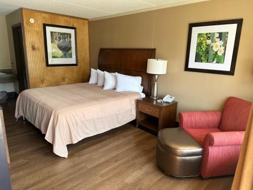 Habitación de hotel con cama y silla en Daniel Boone Motor Inn, en Pikeville