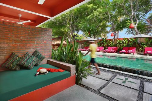 a person walking by a swimming pool next to a resort at PinkCoco Gili Trawangan - Constant Surprises - for Cool Adults Only in Gili Trawangan
