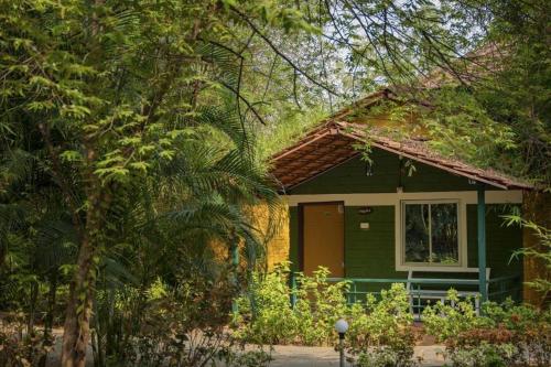 una pequeña casa verde en medio de árboles en Riverfront Resort Dandeli, en Dandeli