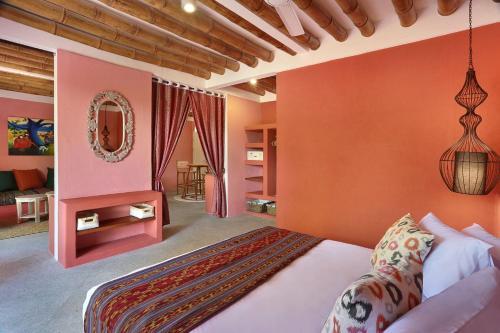 - une chambre avec des murs orange, un lit et un miroir dans l'établissement PinkCoco Gili Trawangan - Constant Surprises - for Cool Adults Only, à Gili Trawangan