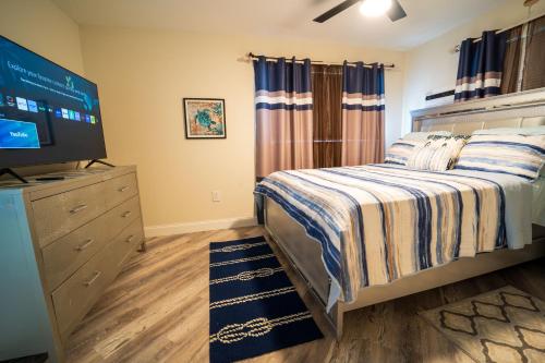 ein Schlafzimmer mit einem Bett und einem Flachbildfernseher in der Unterkunft Bacolet Beach Luxe Pool Cottage in Palm Beach Gardens