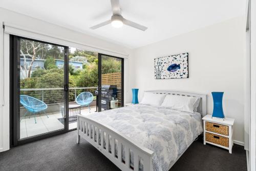 a bedroom with a bed and a balcony at Earth Sea Sky in Wye River