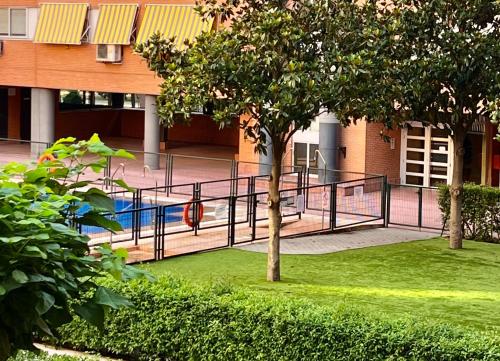 un parque infantil frente a un edificio con un árbol en Suite del Manzanares en Madrid, en Madrid