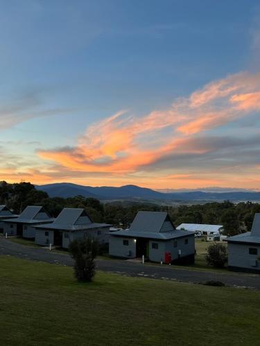 a group of houses with a sunset in the background at Alpine Village Jindabyne in Jindabyne