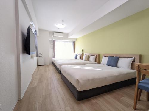 ESLEAD HOTEL Namba South Ⅲ في أوساكا: صف من الاسرة في غرفة الفندق
