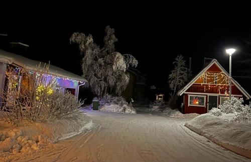 uma casa com luzes de Natal na neve à noite em Adorable 1-bedroom cottage/guesthouse in Kittilä em Kittilä