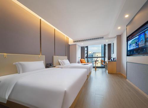 a hotel room with two beds and a flat screen tv at Zhangjiajie Hero Boutique Hotel in Zhangjiajie
