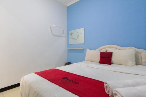 a bedroom with a bed with a red blanket on it at RedDoorz @ Garden Boulevard Citra Raya Tangerang in Tangerang