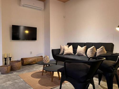 a living room with a black couch and a tv at Nandina, en el bosque y playa in La Pedrera
