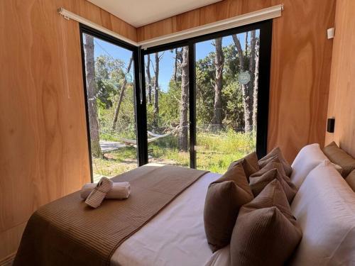 Cama grande en habitación con ventana grande en Nandina, en el bosque y playa en La Pedrera