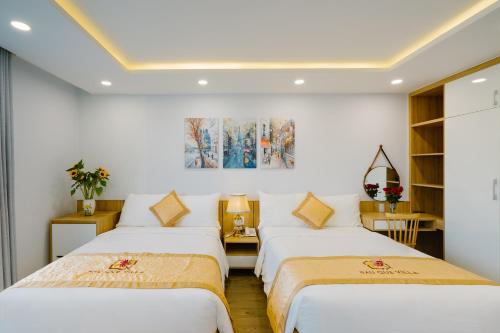 two beds in a room with white walls at LASANTA Villa in Hoi An