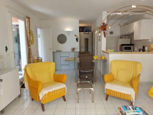 Il comprend un salon avec deux chaises et une cuisine. dans l'établissement Appartement avec Jardin Privatif, Piscines, Activités Eté, Animaux Acceptés - 83380 Roquebrune-sur-Argens - FR-1-768-7, aux Issambres