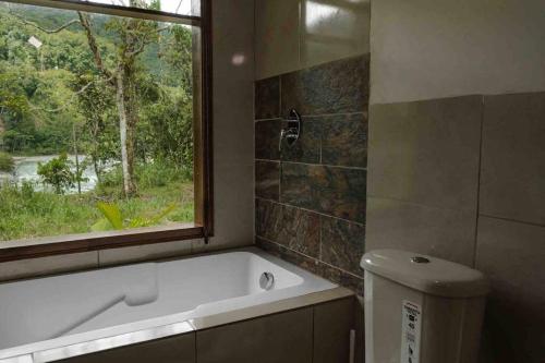 baño con bañera y ventana en Riverside Cabin in Cumandá, near Baños, Ecuador, en Mera