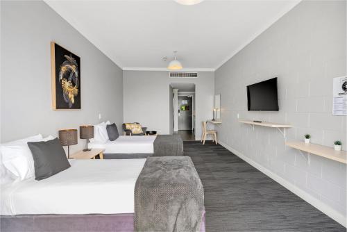 a hotel room with two beds and a tv at Gilligan's Hotel & Resort Cairns in Cairns