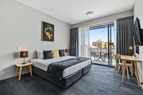 a hotel room with a bed and a balcony at Gilligan's Hotel & Resort Cairns in Cairns