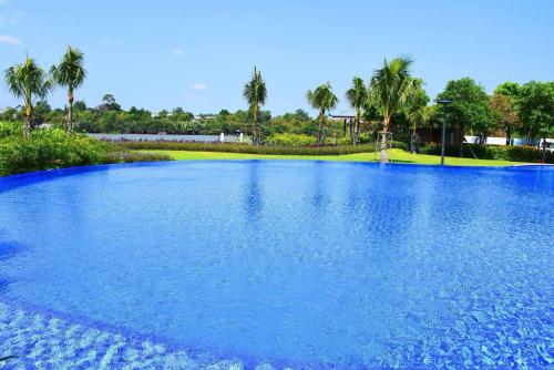 a large pool of blue water with palm trees in the background at White Lotus Hotel - Swanbay in Phước Lý