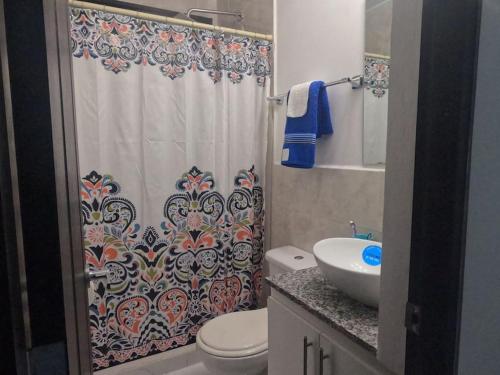 a bathroom with a shower curtain with a toilet and a sink at MADDY Free Wi-Fi, AC in ea Bedrooms, Private Community! in San Miguel