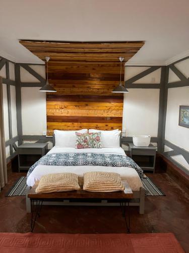 um quarto com uma cama grande e uma cabeceira em madeira em Zamani za kale em Kabuku