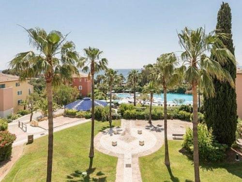 - une vue sur un parc avec des palmiers et une fontaine dans l'établissement Appartement T2 climatisé avec piscine, proche plage, port, commerces et parking privé - FR-1-768-15, aux Issambres