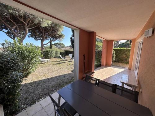 une terrasse couverte avec une table noire et des chaises. dans l'établissement Appartement T2 avec jardin, piscine et parking aux Issambres, proche mer - FR-1-768-34, aux Issambres