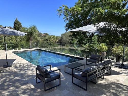 - une piscine avec 2 chaises, une table et un parasol dans l'établissement Villa contemporaine 8/9 pers avec piscine & clim proche plages - 4 étoiles - FR-1-768-43, aux Issambres