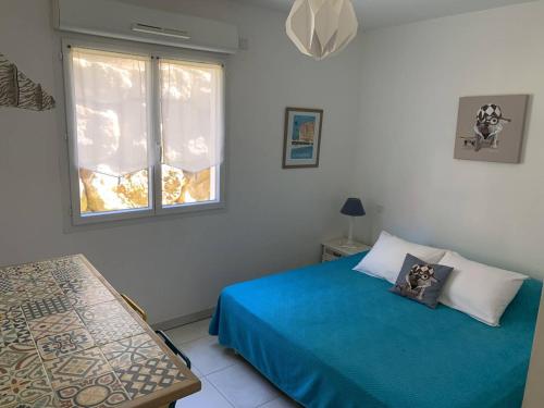 une chambre avec un lit bleu et une fenêtre dans l'établissement Grand T3 aux Issambres avec jardin, proche mer et commerces - FR-1-768-48, aux Issambres