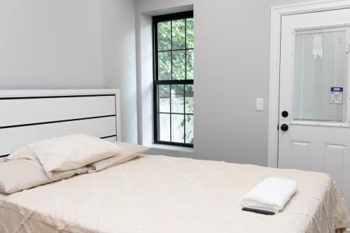 a white bedroom with a bed with two towels on it at Misbau home in Brooklyn