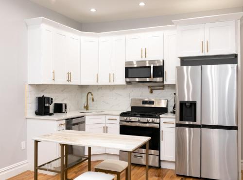 eine Küche mit weißen Schränken und einem Kühlschrank aus Edelstahl in der Unterkunft Misbau home in Brooklyn