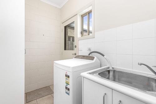 Un baño blanco con lavabo y lavadora. en Edwards, en Apollo Bay