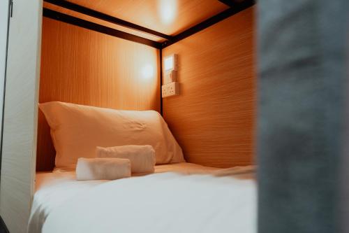 a bedroom with a white bed with a wooden headboard at Code Hostel at Lavender in Singapore