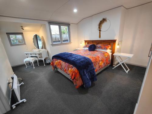 1 dormitorio con cama, mesa y espejo en Peaceful by the Park en Invercargill