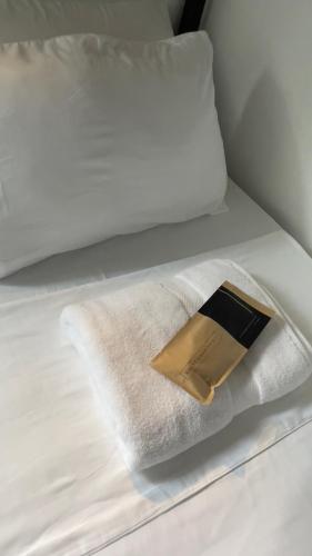 a white towel and a book on a bed at LArtista Hostel in Puerto Princesa City