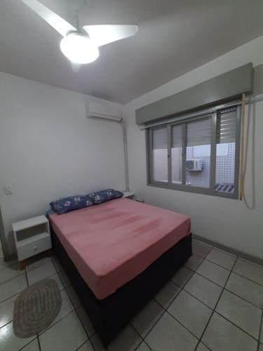1 dormitorio con cama y ventana en Capao Canoa - Próximo Mar Centro, en Capão da Canoa