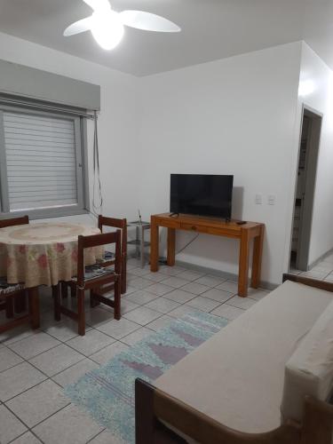 a living room with a tv and a table at Capao Canoa - Próximo Mar Centro in Capão da Canoa