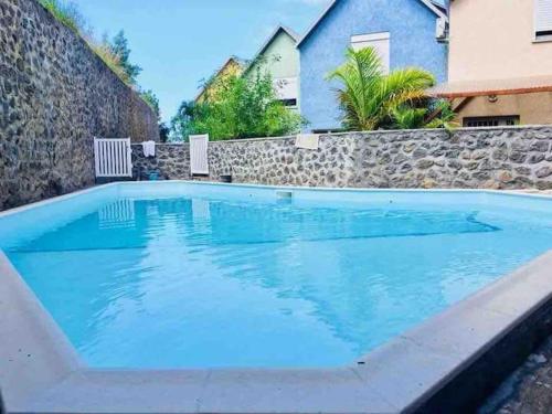 a large blue swimming pool with a stone wall at Ocean View Chambre in Saint-Leu