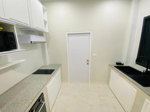 a white kitchen with white cabinets and a door at Krabi Aonang & Alpha villa in Ao Nam Mao