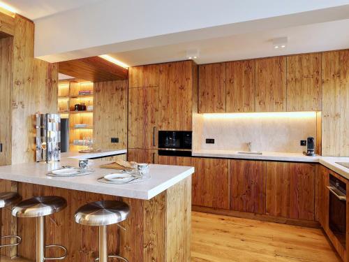 une cuisine avec des murs en bois et un grand îlot avec des tabourets de bar dans l'établissement Appartement duplex à Courchevel 1850 - 6 pers, 3 chambres, centre station - FR-1-564-116, à Courchevel