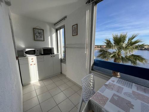 une cuisine avec une table et une vue sur l'océan dans l'établissement Appartement 2 pièces avec piscine proche commerces au Barcarès - FR-1-81-604, au Barcarès