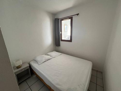 une petite chambre avec un lit et une fenêtre dans l'établissement Appartement 2 pièces avec piscine proche commerces au Barcarès - FR-1-81-604, au Barcarès