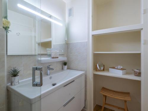 une salle de bain blanche avec un lavabo et un miroir dans l'établissement Appartement rénové avec balcon | WIFI | Casier à skis - FR-1-645-50, à Huez