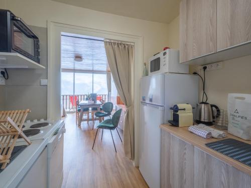 Il comprend une cuisine équipée d'un réfrigérateur et d'une table avec des chaises. dans l'établissement Appartement rénové avec balcon | WIFI | Casier à skis - FR-1-645-50, à Huez