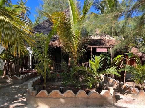 a house with palm trees in front of it at Dreamland Bungalows Michamvi Kae in Michamvi