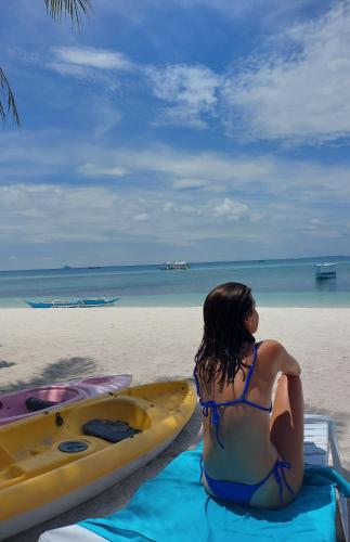a woman sitting on the beach next to a kayak at Avila's Horizon Dive Resort Malapascua in Malapascua Island
