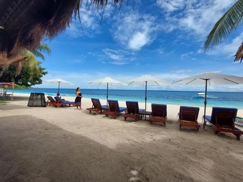 a group of chairs and umbrellas on a beach at Avila's Horizon Dive Resort Malapascua in Malapascua Island