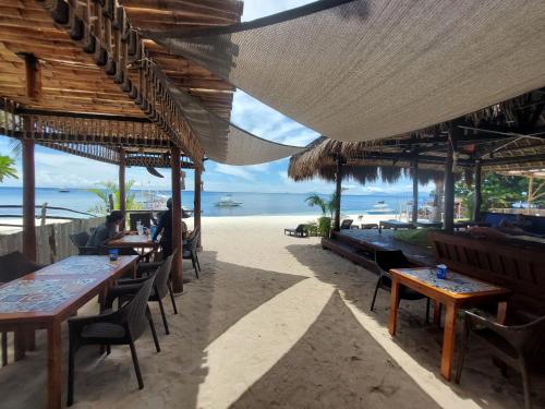 a restaurant with tables and chairs on the beach at Avila's Horizon Dive Resort Malapascua in Malapascua Island