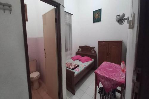 een slaapkamer met een bed en een tafel met een roze tafelkleed bij SPOT ON 93324 Hadi Homestay Syariah in Sleman
